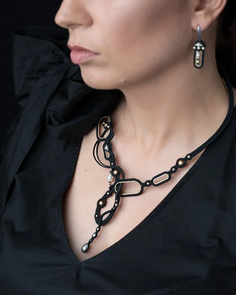 Wystudiowany i ręcznie wyhaftowany czarny naszyjnik o linearnej formie z dodatkiem kryształowych pereł